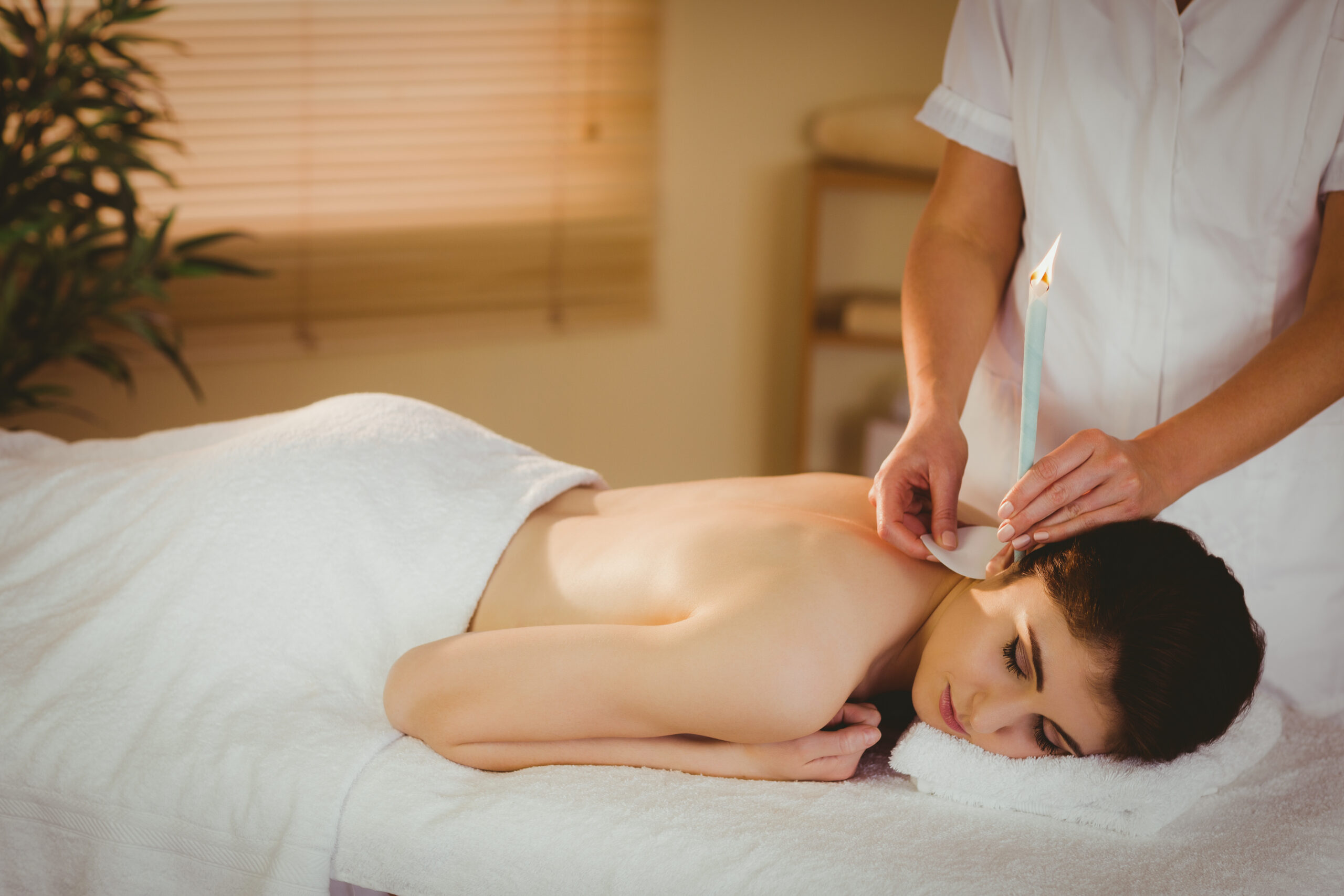 Young woman getting ear candling treatment in therapy room